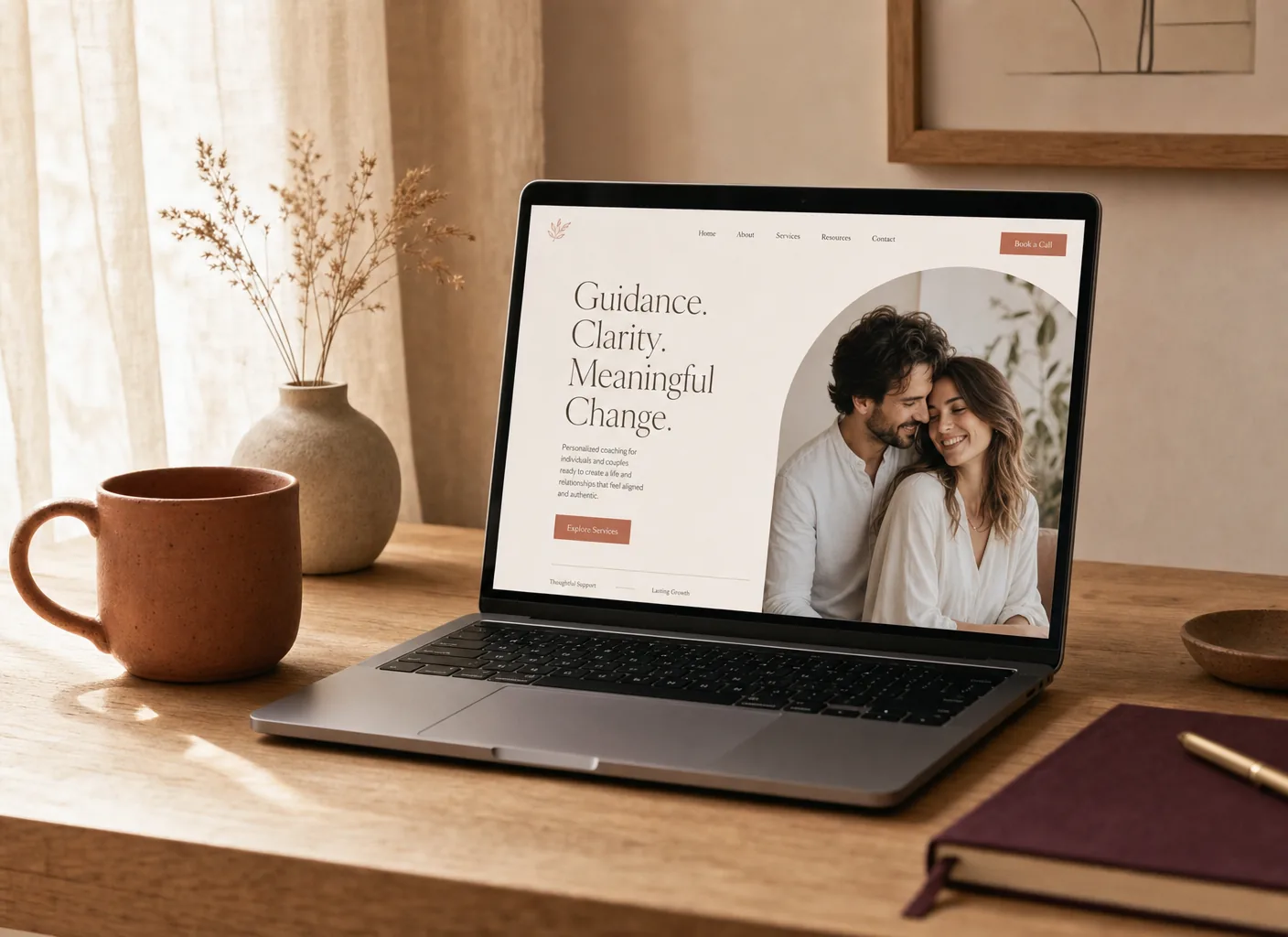 A laptop on a warm desk displaying an elegant cream and terracotta coaching website